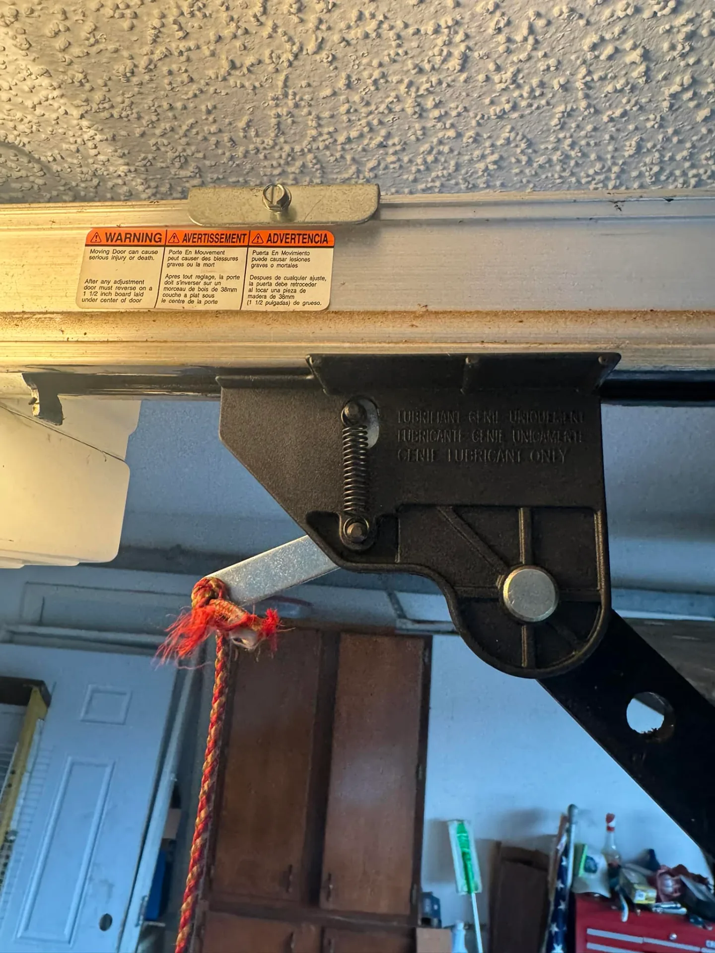 Garage door opener emergency release mechanism with warning label