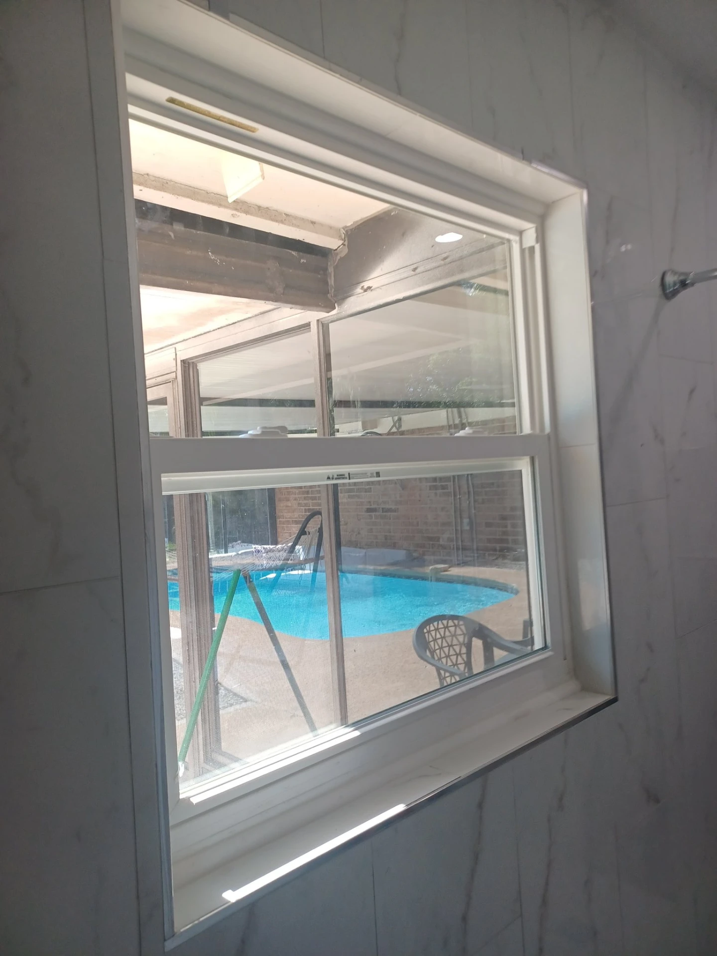 New window installation on marble tile wall with pool view